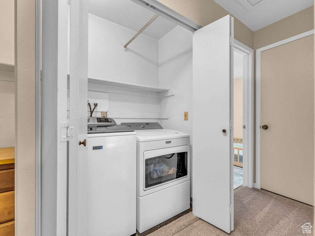 Washroom with laundry area, washer and clothes dryer, and light carpet
