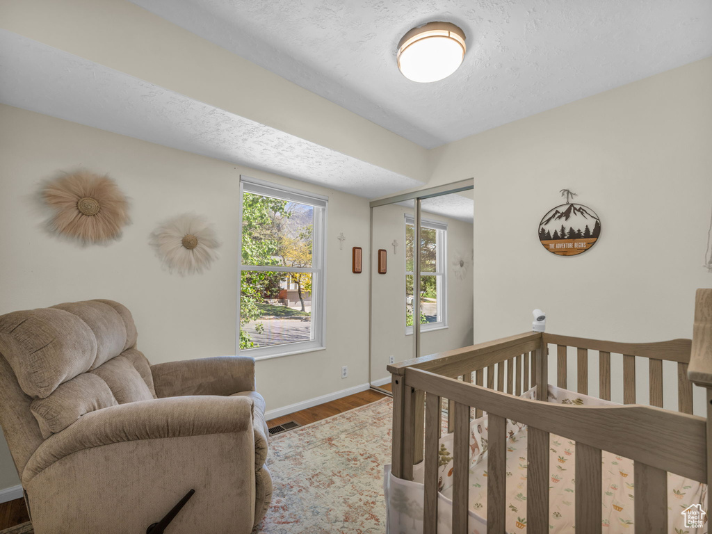 Bedroom with visible vents, a closet, wood finished floors, baseboards, and a textured ceiling
