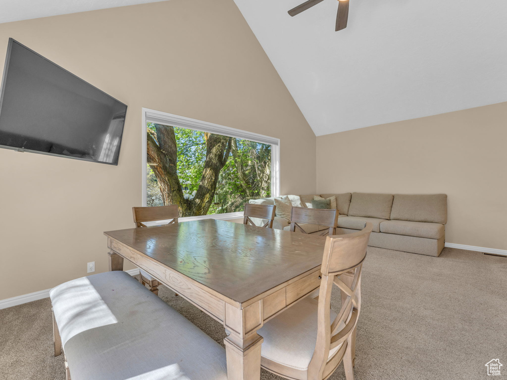 Carpeted dining space with a ceiling fan, baseboards, and lofted ceiling