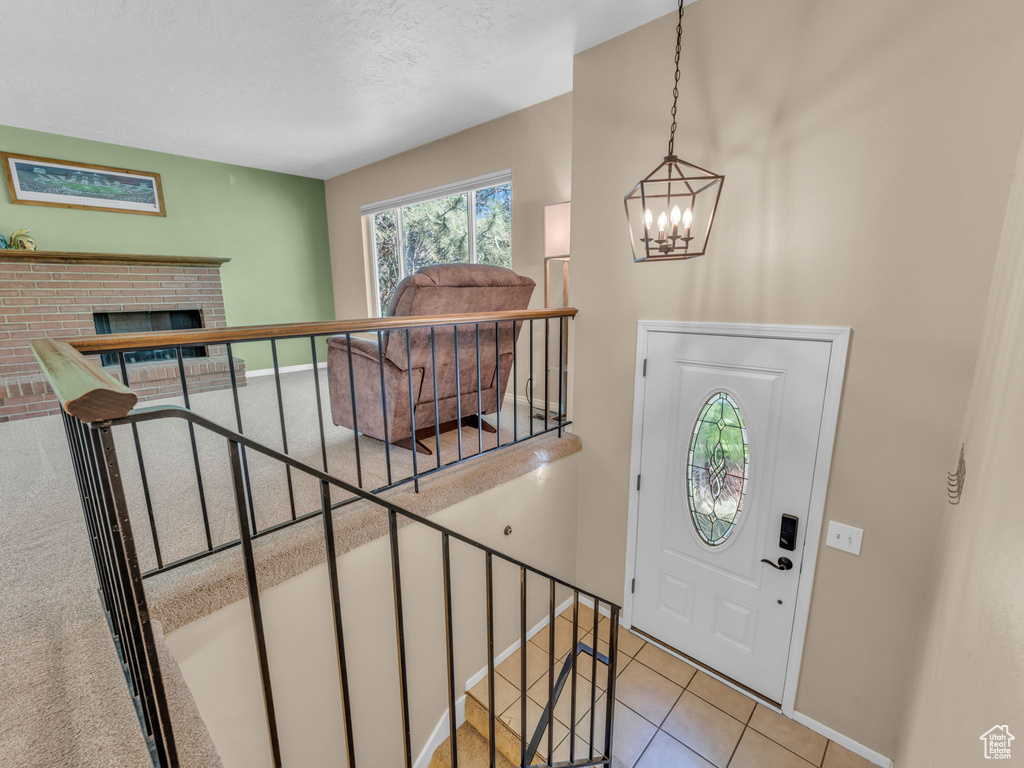 Entrance foyer featuring a fireplace, baseboards, a textured ceiling, tile patterned floors, and a notable chandelier