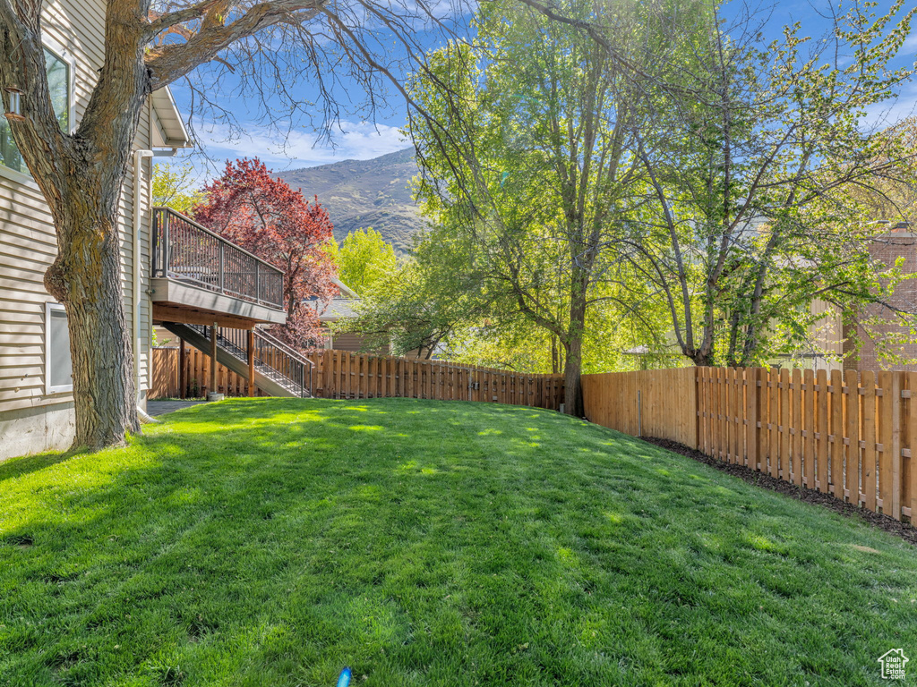 View of yard featuring a fenced backyard, stairs, and a deck with mountain view