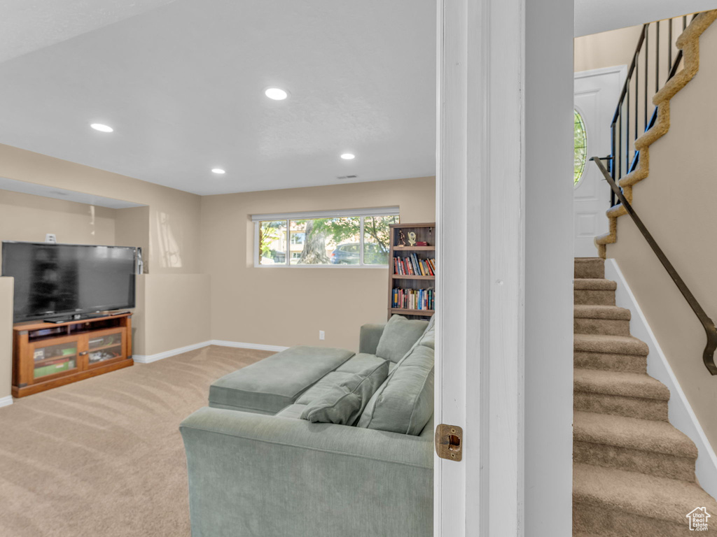 Carpeted living area with baseboards, recessed lighting, and stairs