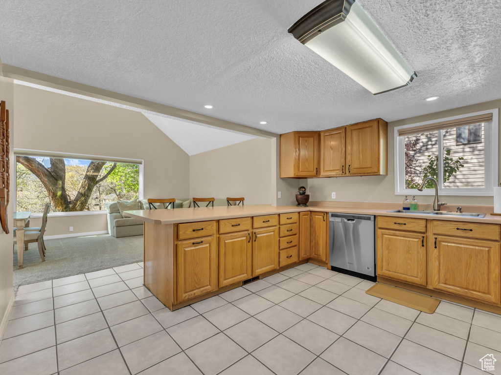 Kitchen with a sink, a textured ceiling, dishwasher, and light countertops