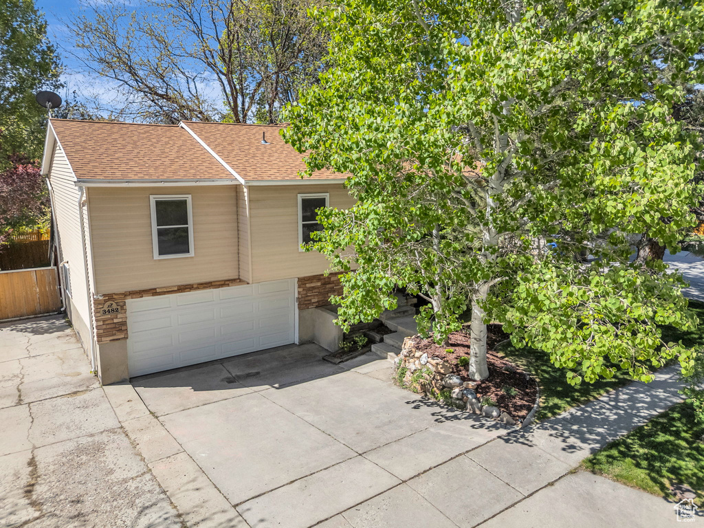 View of front of home featuring roof with shingles, concrete driveway, and a garage