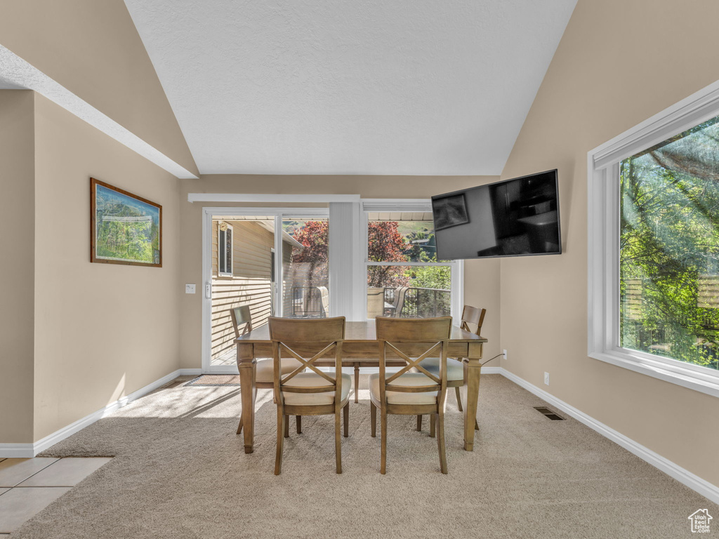 Dining space with baseboards, light carpet, and vaulted ceiling