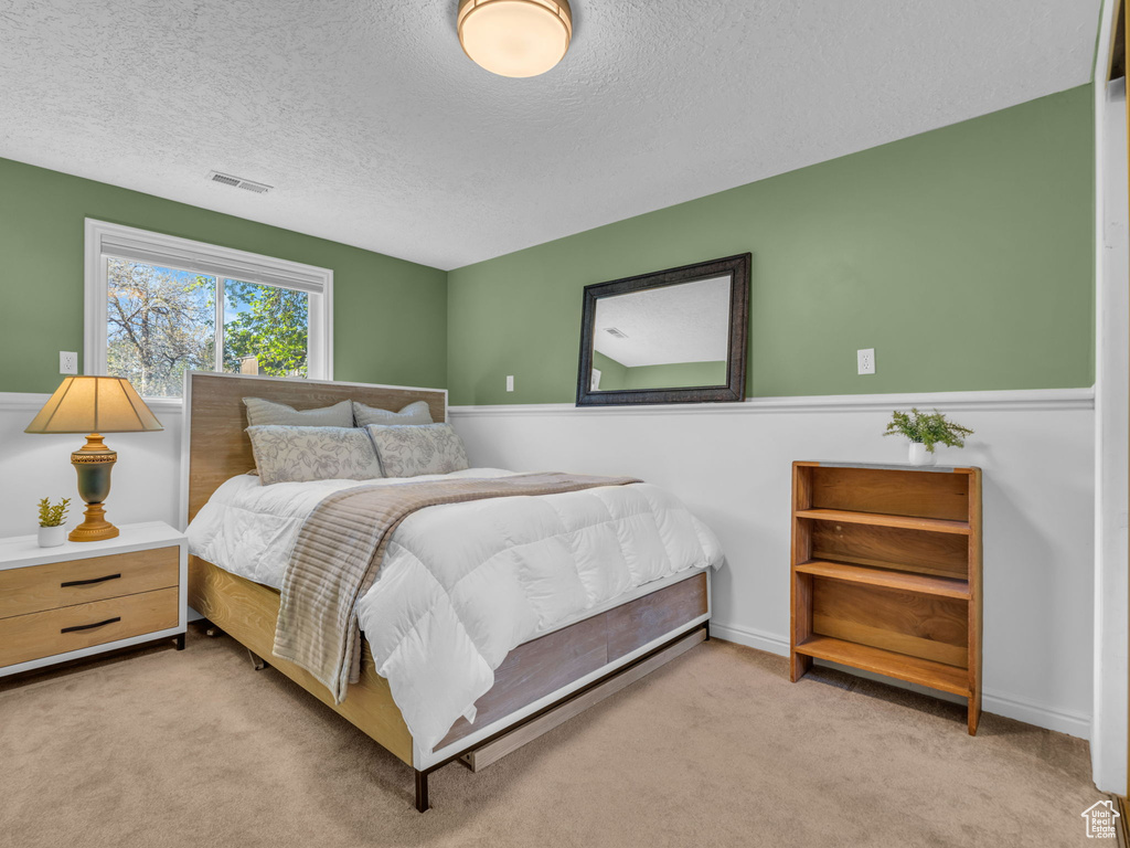Carpeted bedroom featuring visible vents and a textured ceiling