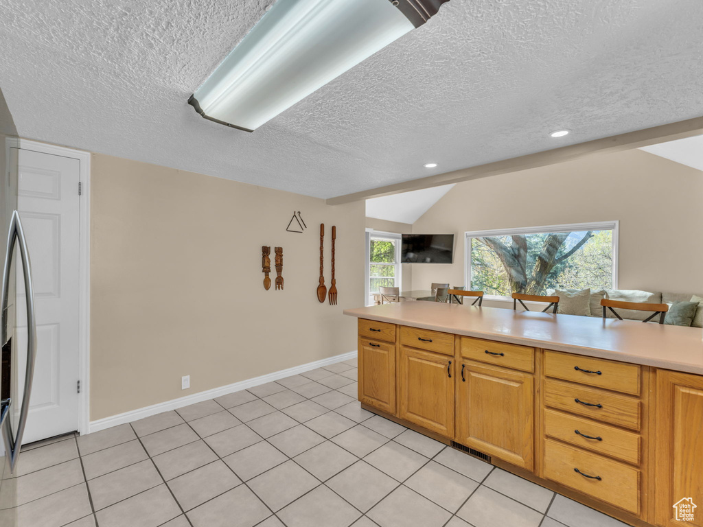 Kitchen with light countertops, vaulted ceiling, a textured ceiling, and open floor plan