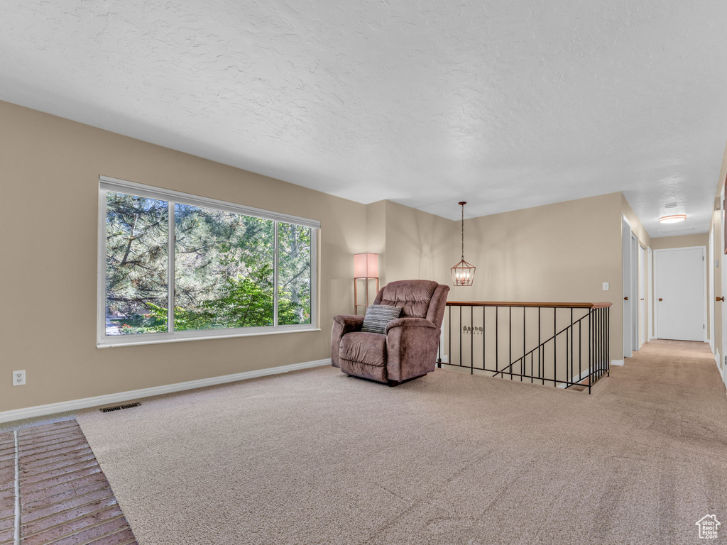 Living area with carpet floors, baseboards, an upstairs landing, and visible vents