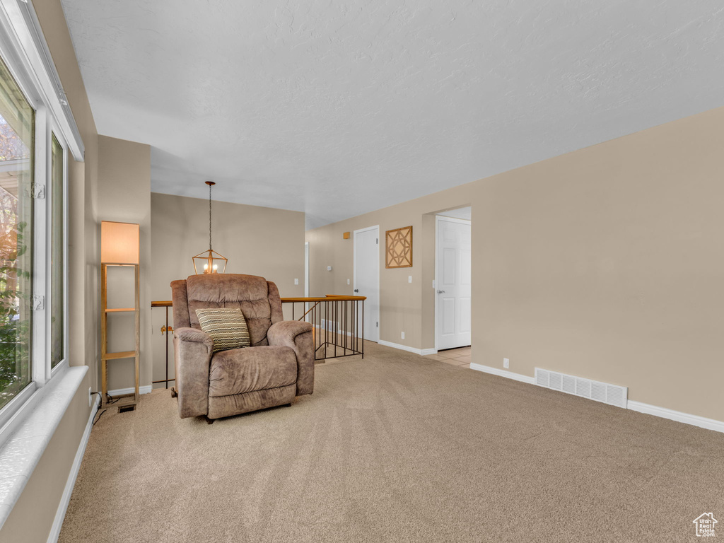 Living area with baseboards, carpet, an upstairs landing, and visible vents