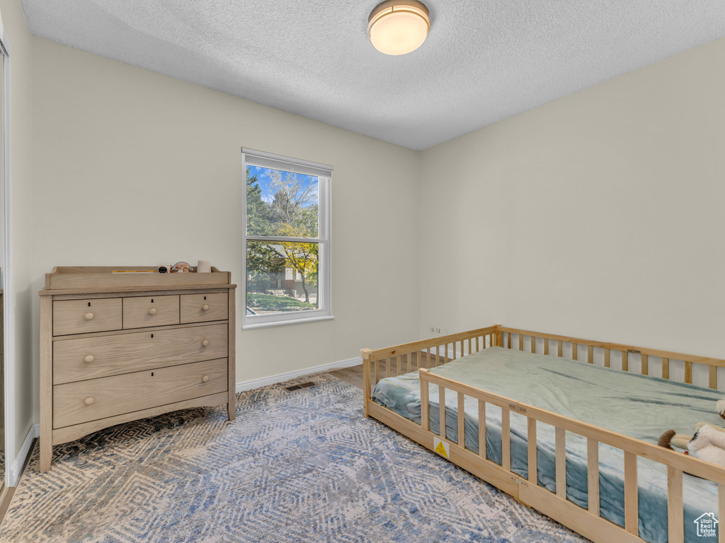 Bedroom featuring a textured ceiling, baseboards, and carpet