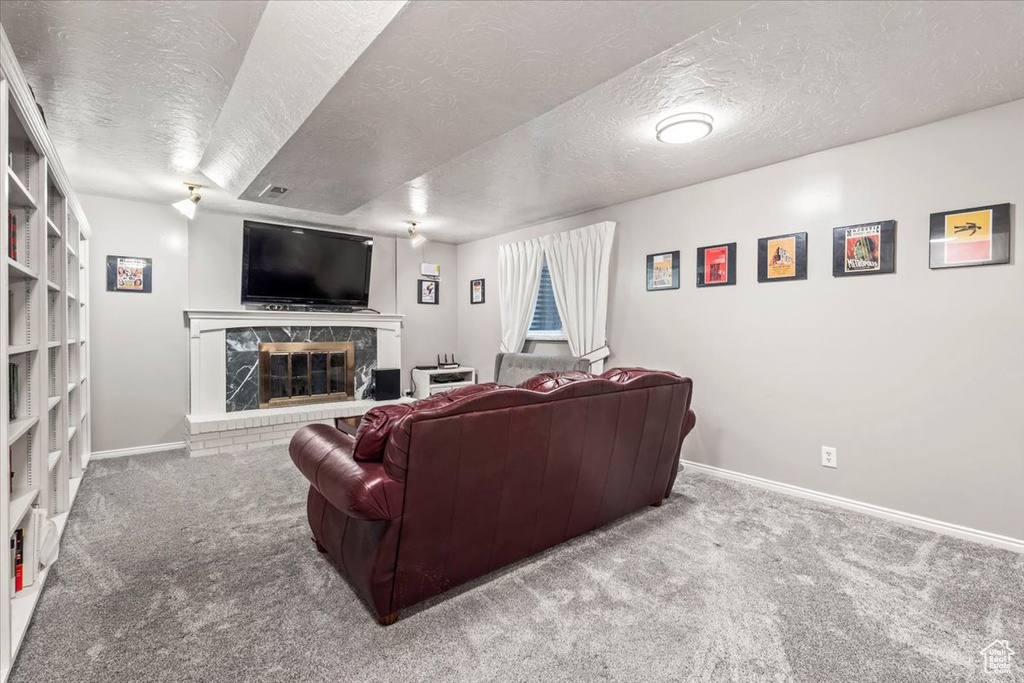 Living area featuring baseboards, a fireplace, carpet flooring, and a textured ceiling