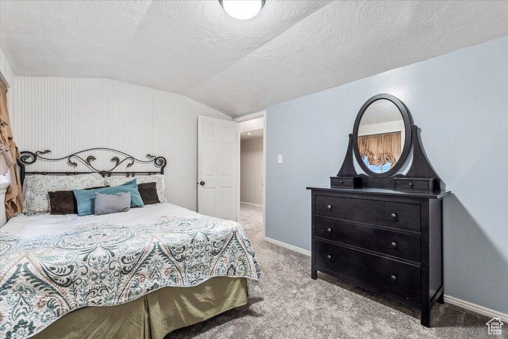 Bedroom with carpet floors, a textured ceiling, baseboards, and vaulted ceiling