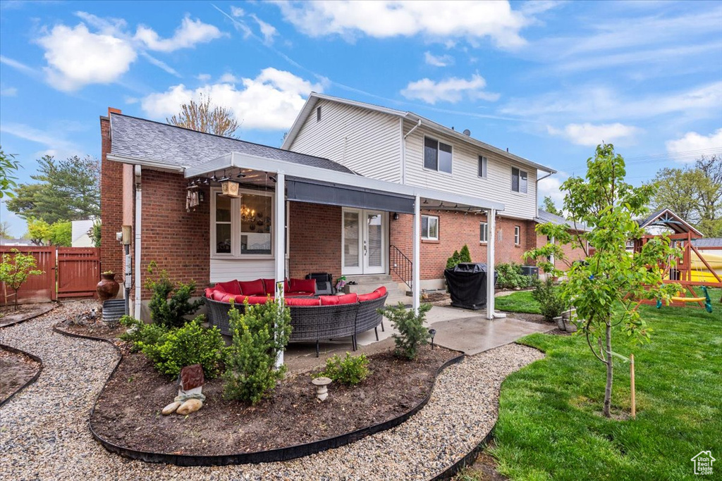 Back of property with brick siding, an outdoor living space, french doors, and a patio