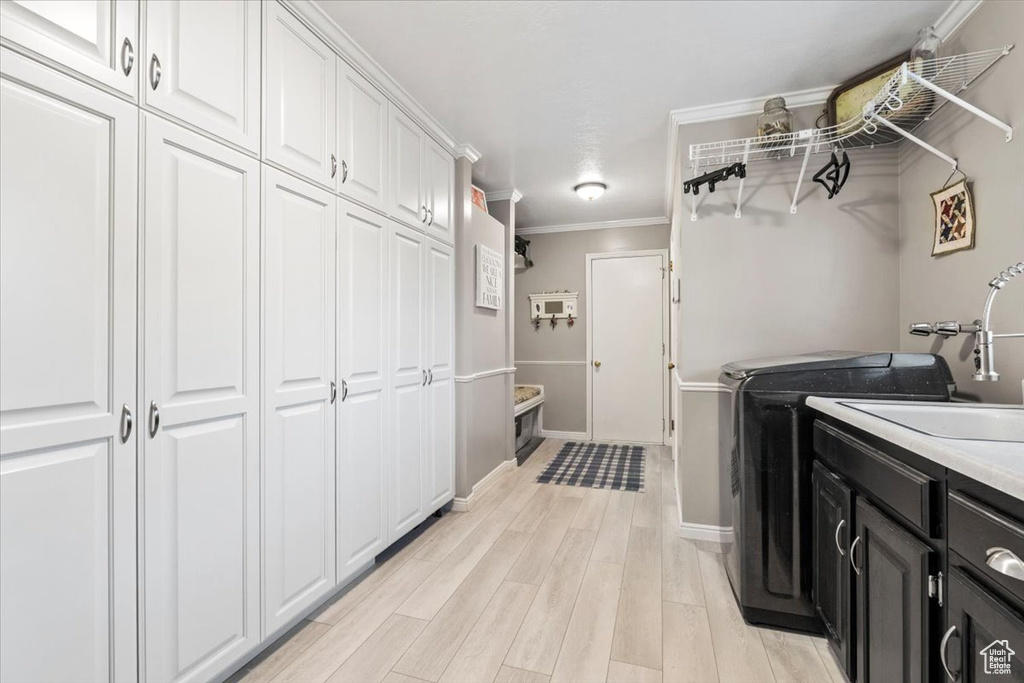 Laundry area with cabinet space, baseboards, ornamental molding, light wood-style flooring, and washer and dryer