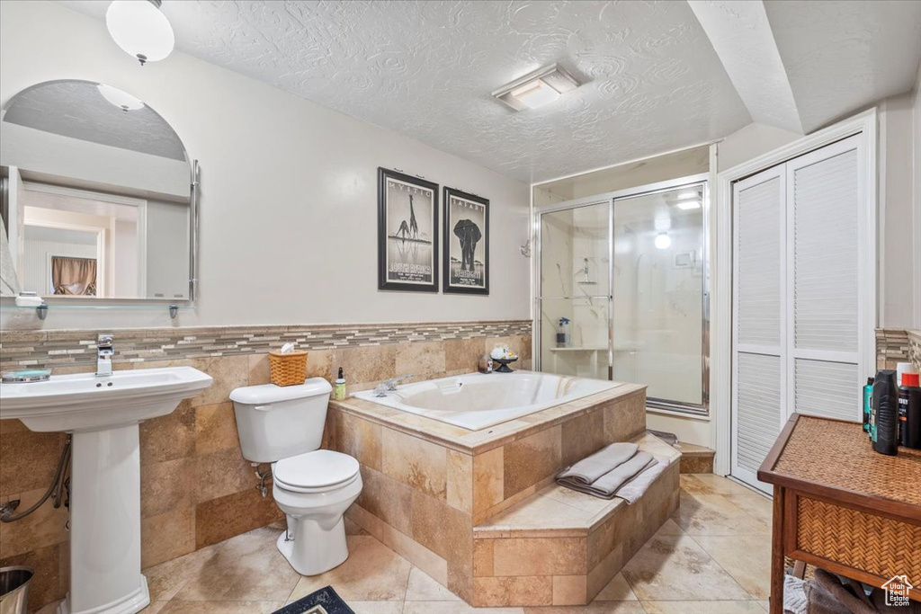 Full bathroom with a garden tub, a textured ceiling, a stall shower, a sink, and toilet