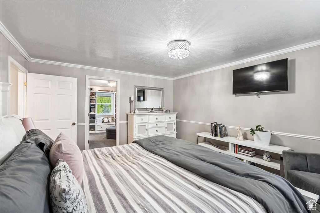 Bedroom with crown molding, a textured ceiling, and an inviting chandelier