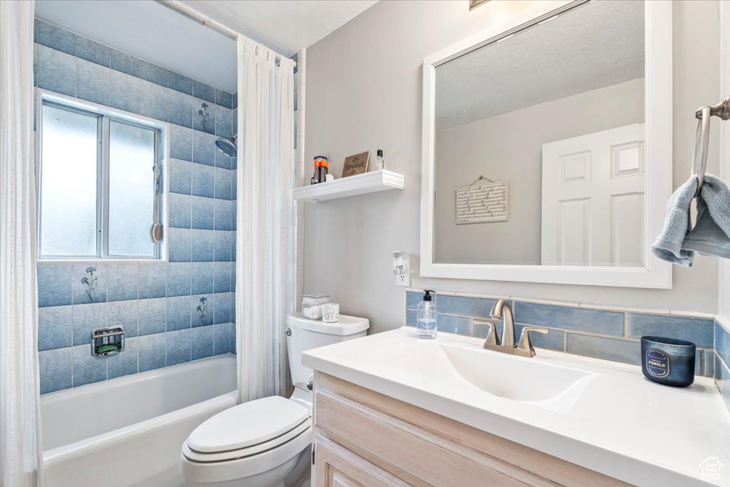 Bathroom with vanity, toilet, and shower / bath combination with curtain