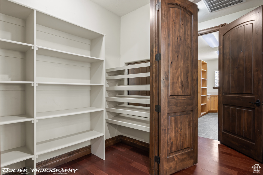 Walk in closet with visible vents and dark wood-style floors