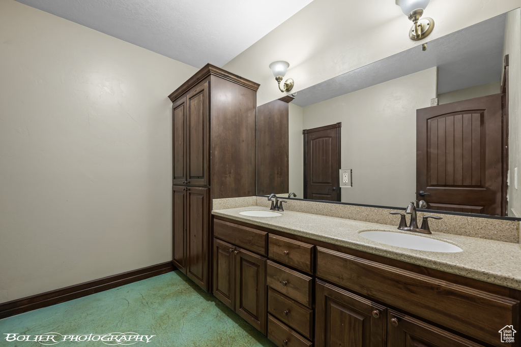 Bathroom featuring a sink, baseboards, and double vanity