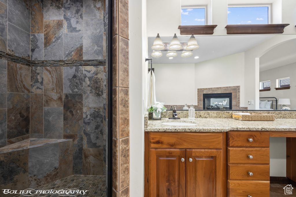 Bathroom featuring vanity, a tiled fireplace, and a tile shower