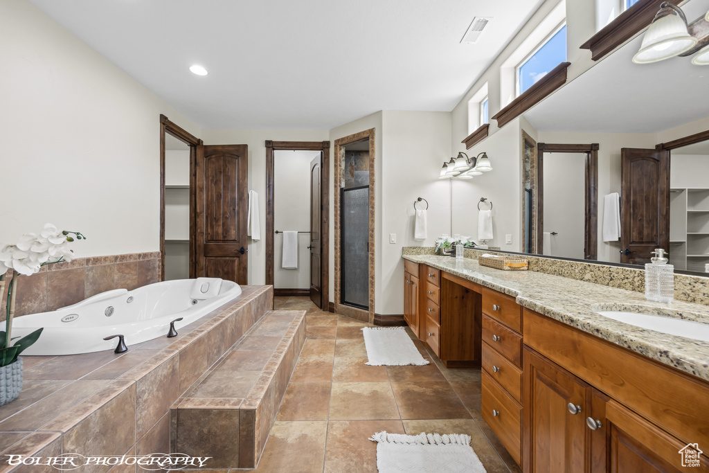 Full bath featuring vanity, visible vents, a tub with jets, and a stall shower