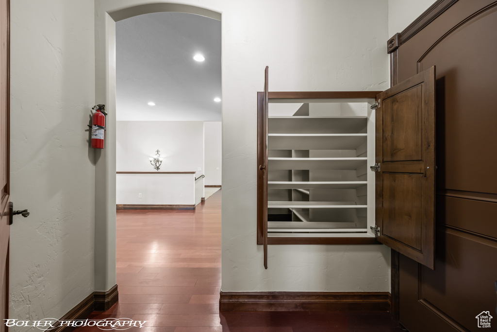 Hall with wood-type flooring, arched walkways, baseboards, and recessed lighting