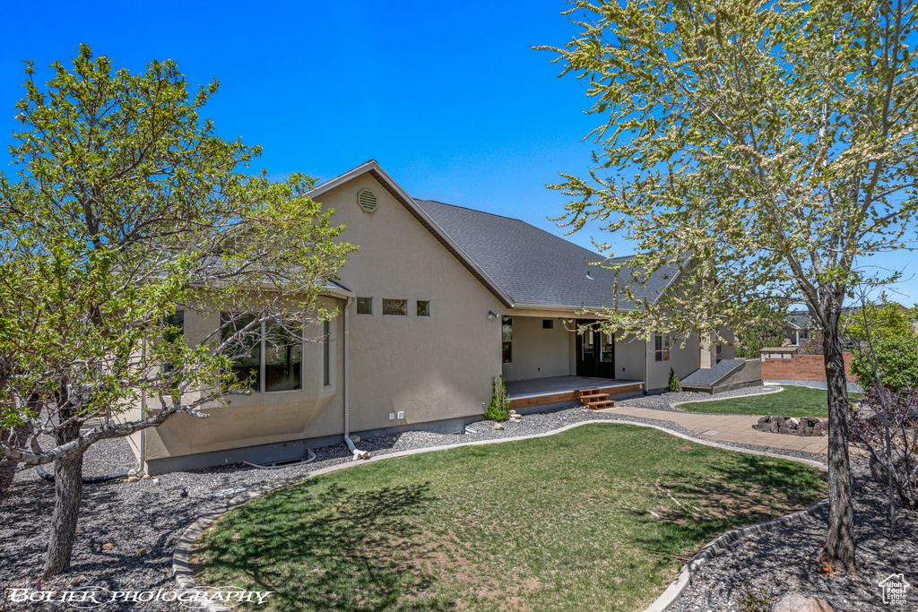 View of front of house with a porch, a front lawn, roof with shingles, and stucco siding