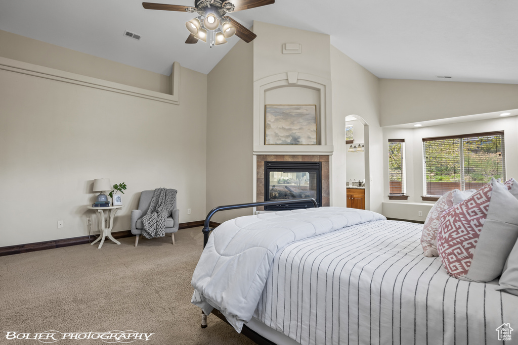 Carpeted bedroom with high vaulted ceiling, visible vents, baseboards, and a tile fireplace