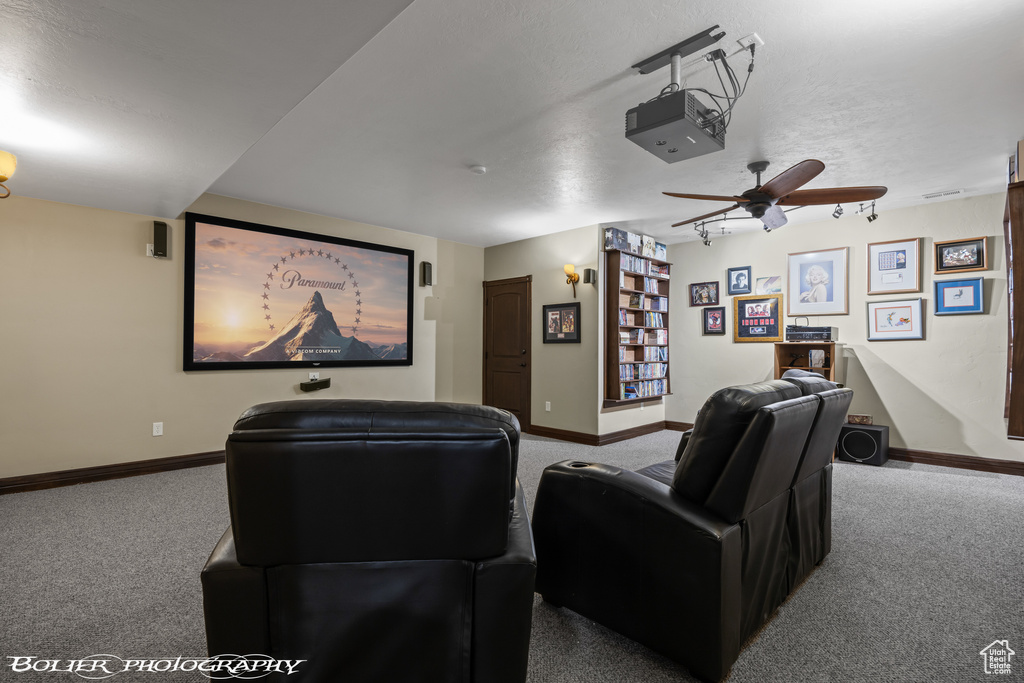 Carpeted home theater featuring baseboards and a ceiling fan