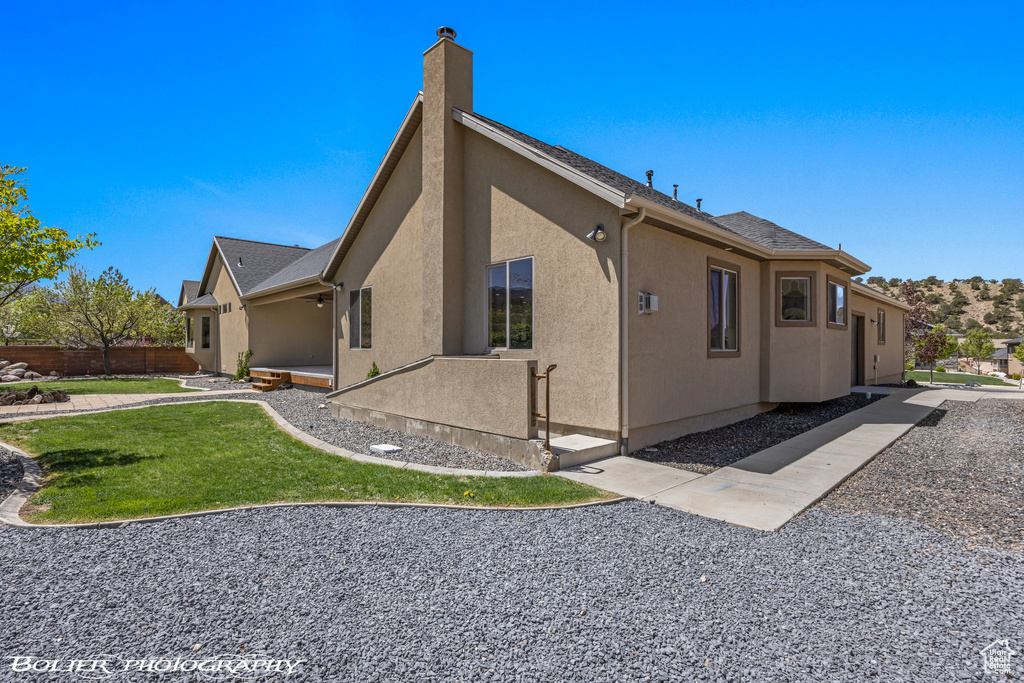 View of home\\\\\\\\\\\\\\\'s exterior featuring fence, a lawn, stucco siding, and a chimney