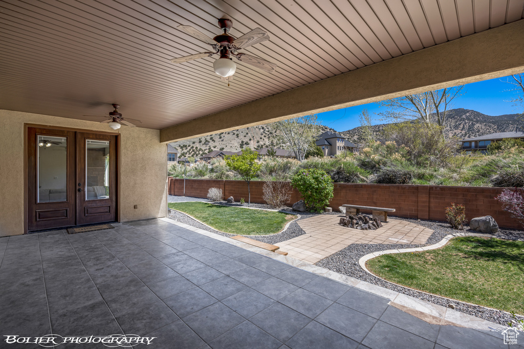 View of patio featuring a mountain view, a ceiling fan, french doors, and a fenced backyard