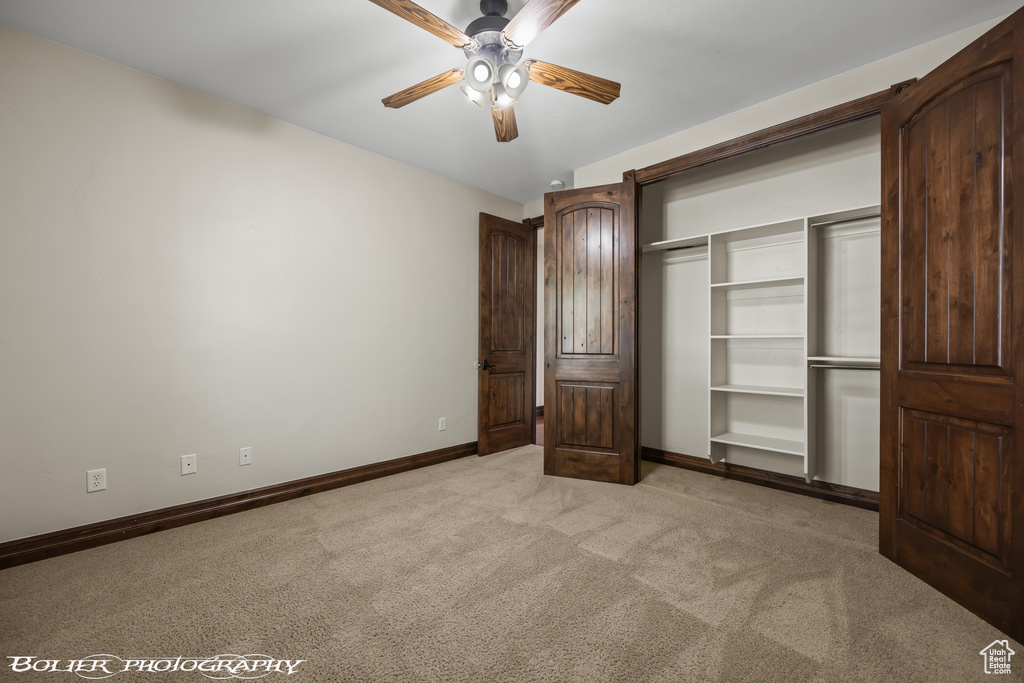 Unfurnished bedroom with light colored carpet, a ceiling fan, baseboards, and a closet