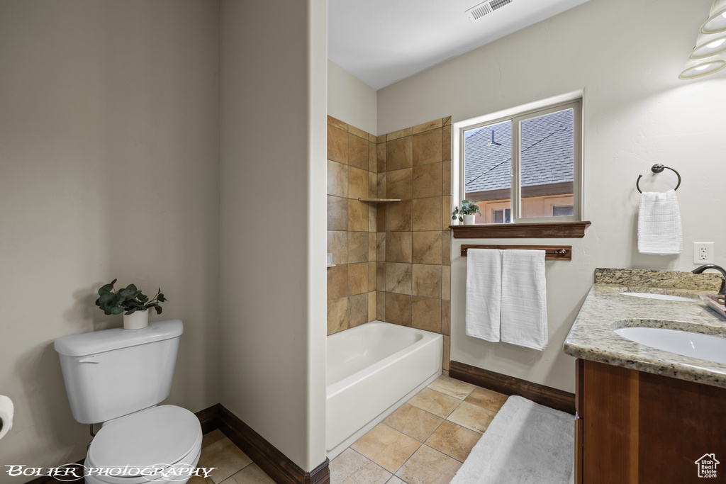 Bathroom featuring a sink, double vanity, toilet, baseboards, and visible vents