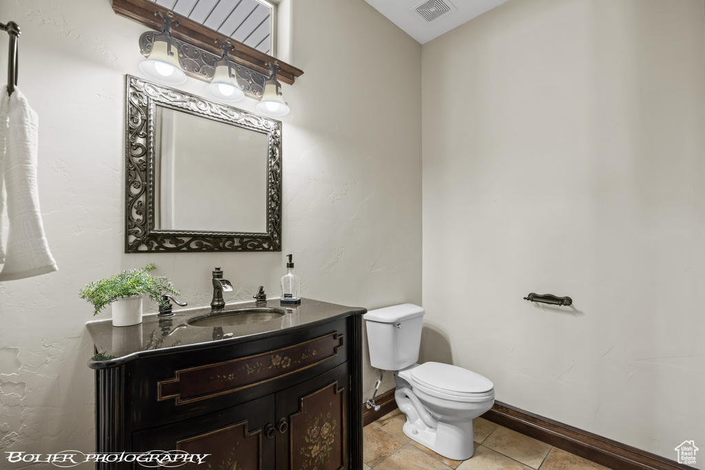 Half bath featuring visible vents, tile patterned flooring, vanity, toilet, and baseboards
