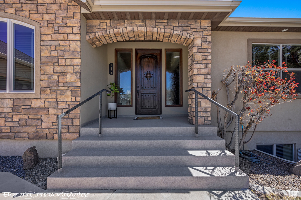 Doorway to property with visible vents, stone siding, and stucco siding