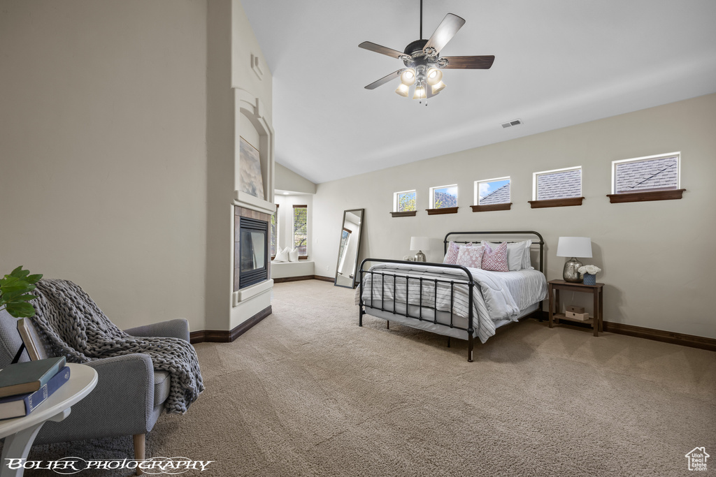 Carpeted bedroom with ceiling fan, a fireplace, high vaulted ceiling, baseboards, and visible vents