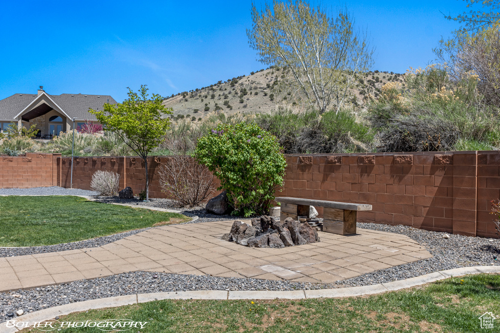 View of yard featuring fence, a mountain view, and a patio area