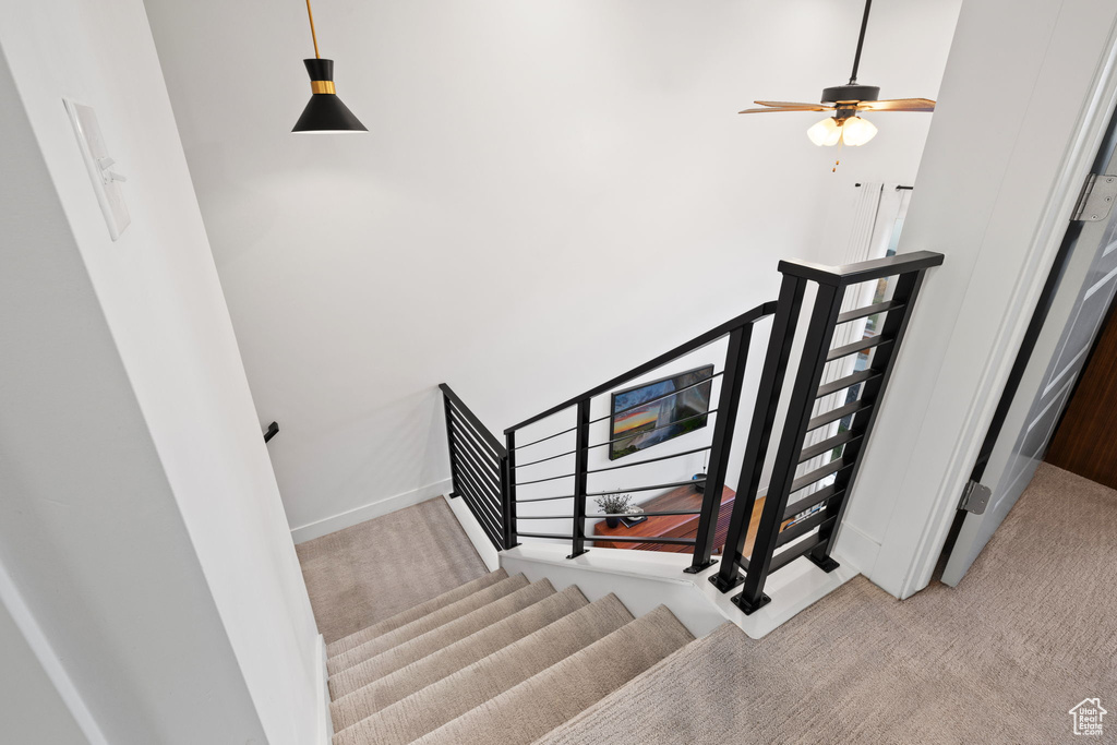 Stairway featuring baseboards, carpet, and a ceiling fan