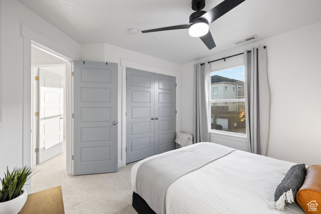 Bedroom featuring visible vents, a closet, ceiling fan, and light colored carpet
