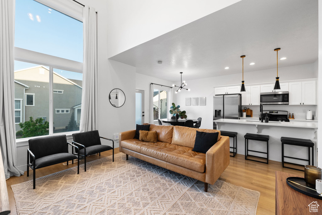 Living room featuring an inviting chandelier, recessed lighting, and light wood-type flooring