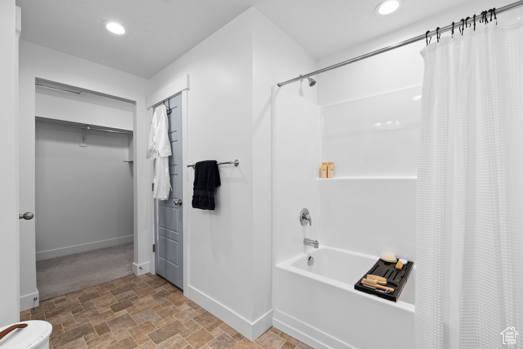 Bathroom with baseboards, recessed lighting, stone finish flooring, and shower / bathtub combination with curtain