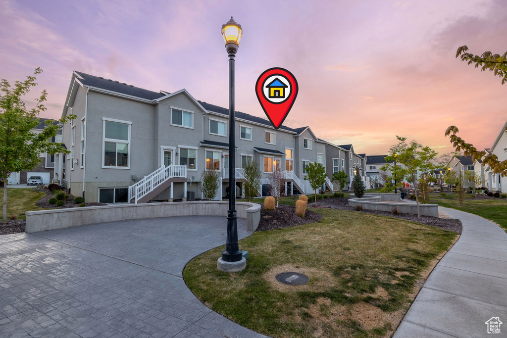 View of front of property featuring stairway, stucco siding, a yard, and a residential view
