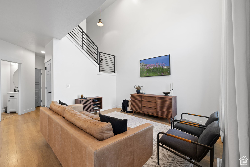 Living room featuring a high ceiling, light wood-style floors, recessed lighting, baseboards, and stairway
