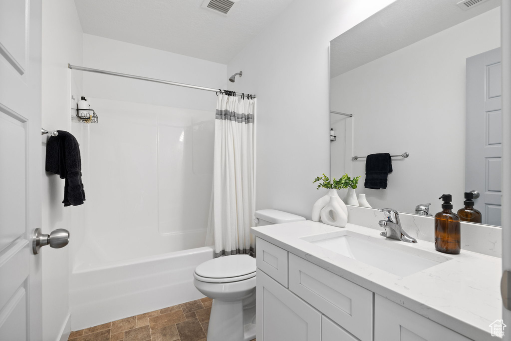 Full bathroom with visible vents, shower / bath combination with curtain, toilet, and vanity