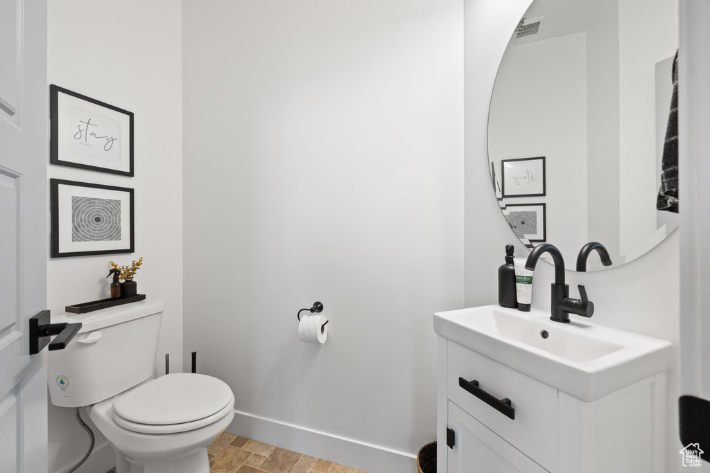 Bathroom with toilet, baseboards, visible vents, and vanity