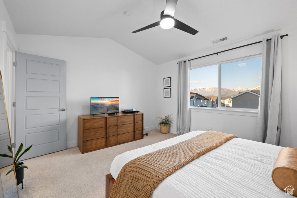 Carpeted bedroom featuring ceiling fan, lofted ceiling, and visible vents