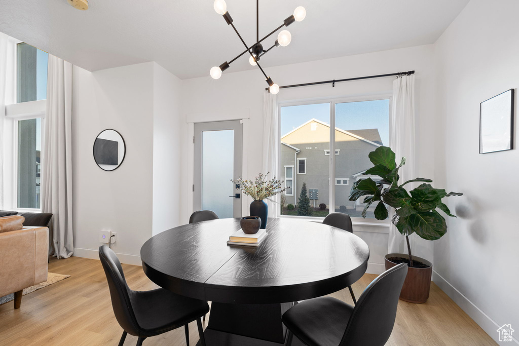 Dining area featuring baseboards, light wood finished floors, and a chandelier