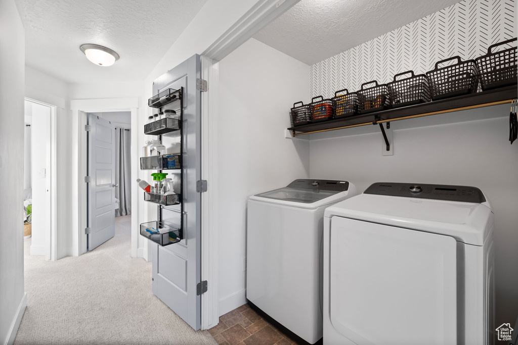 Clothes washing area with baseboards, laundry area, washing machine and dryer, and a textured ceiling