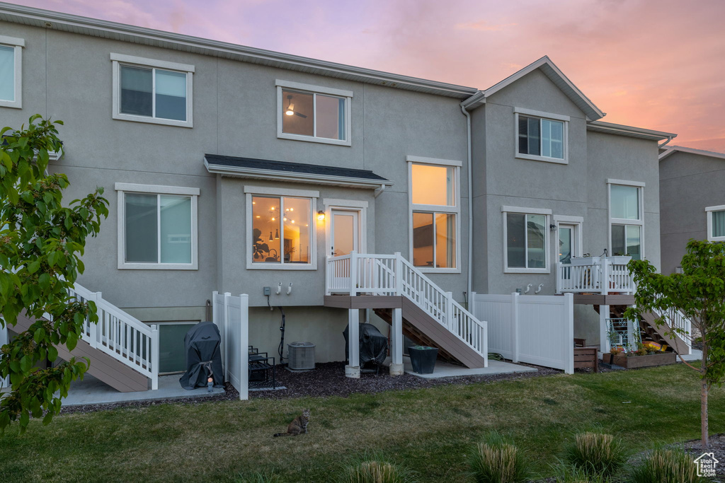 Back of house with stucco siding, a yard, and stairway