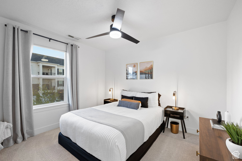 Carpeted bedroom with a ceiling fan, baseboards, and visible vents